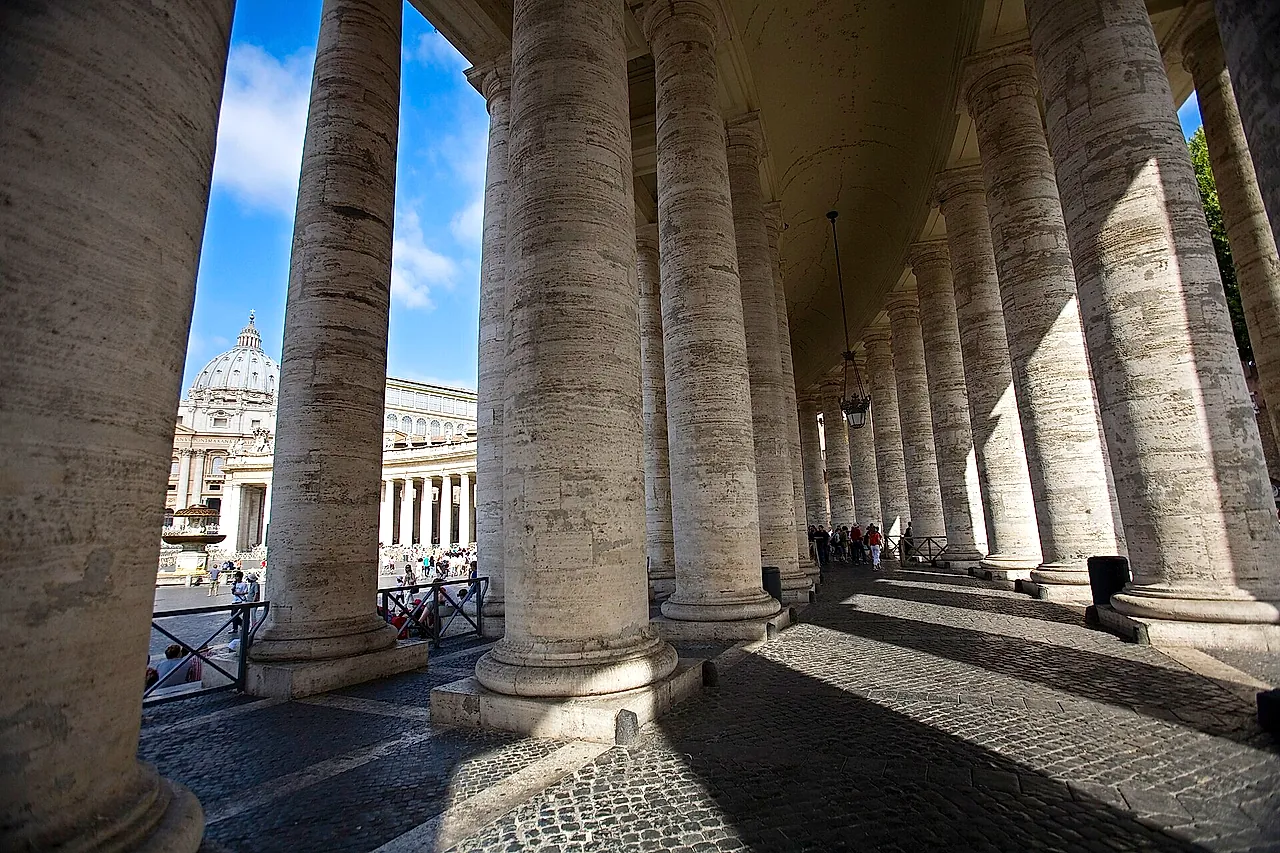 The curved Bernini colonnade of St Peter's Square seen from the square, with its rows of stone columns topped by statues of saints